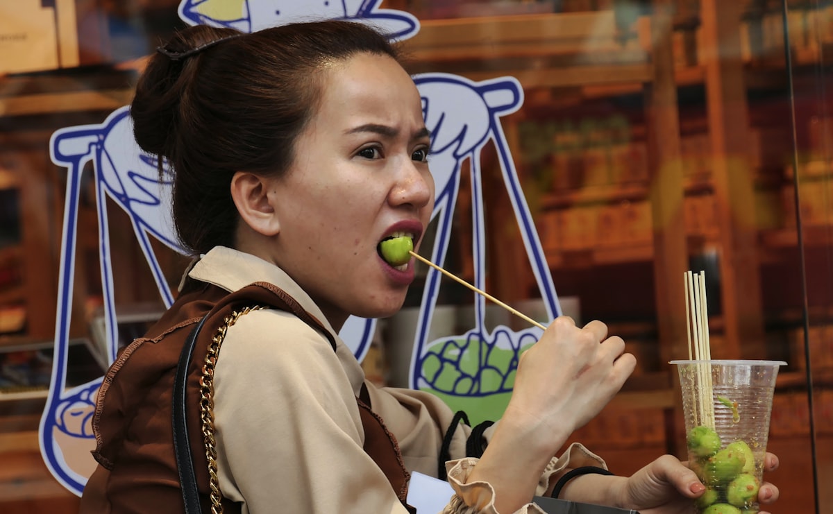 woman in white and brown school uniform holding green apple fruit