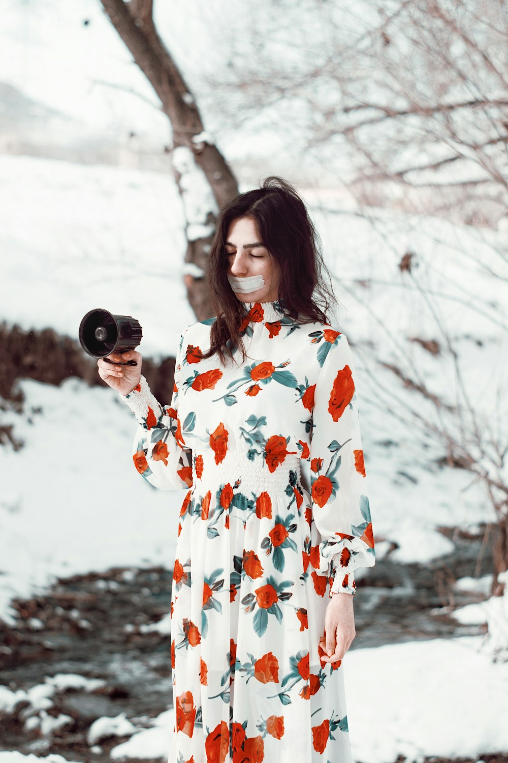 woman in white and red floral dress holding black camera