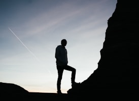silhouette of man standing on rock during sunset