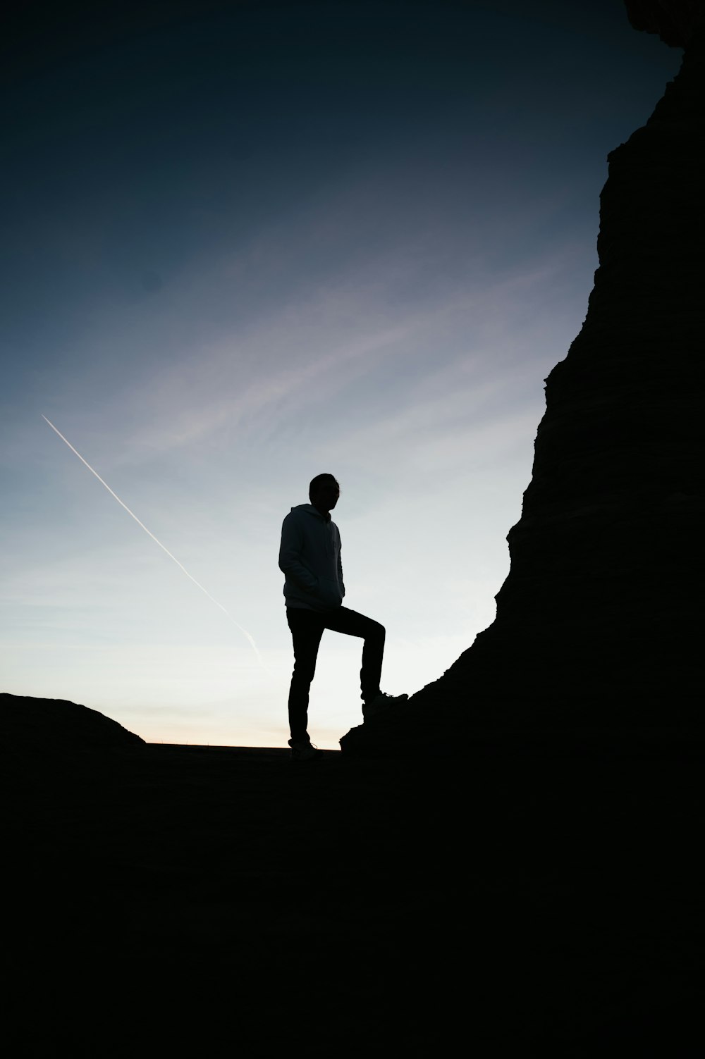 silueta de hombre de pie sobre una roca durante la puesta de sol