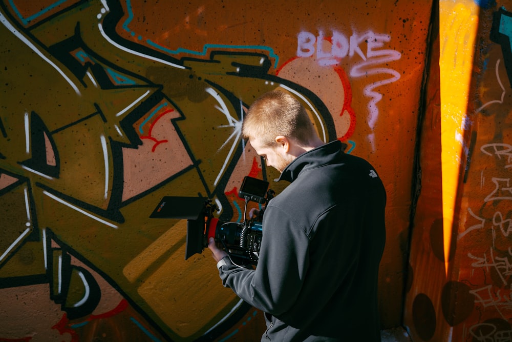 man in black hoodie holding black camera