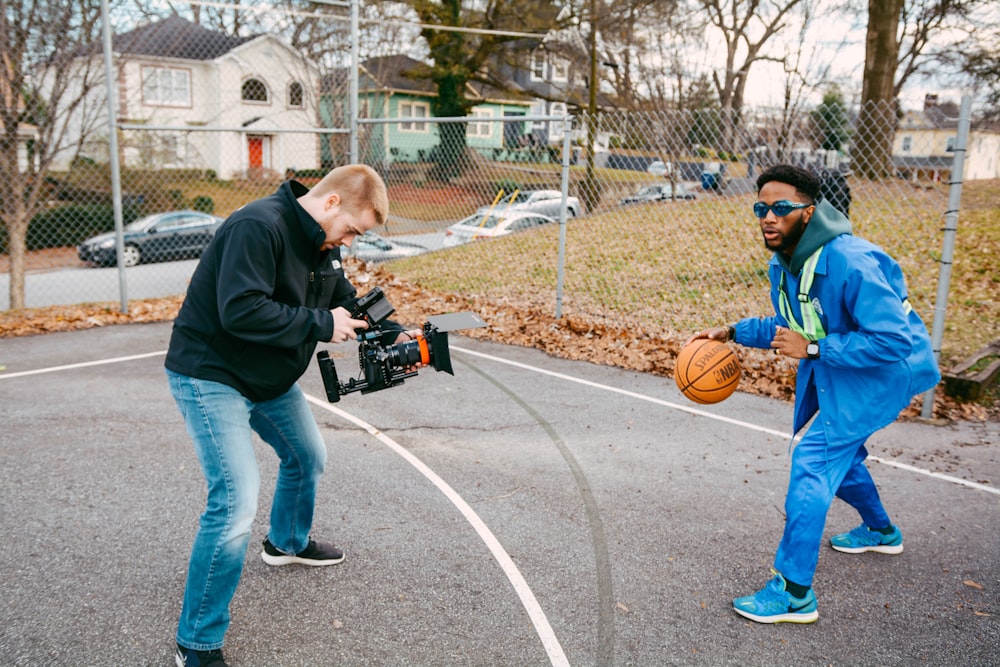 man in black jacket and blue denim jeans holding basketball during daytime