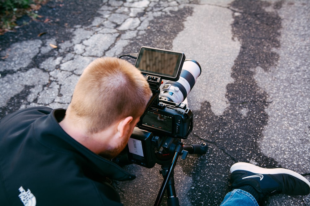 man in black jacket holding black dslr camera