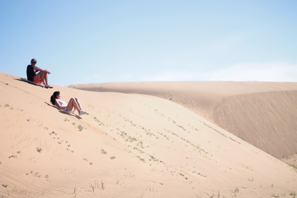 woman in black tank top sitting on sand dunes during daytime