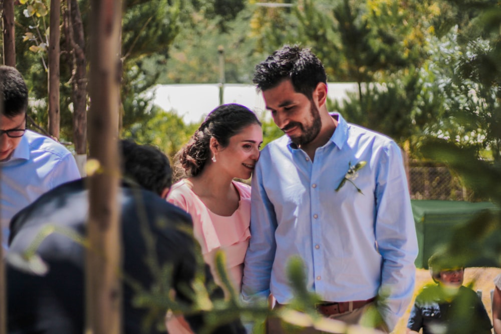 man in white dress shirt standing beside woman in pink dress shirt