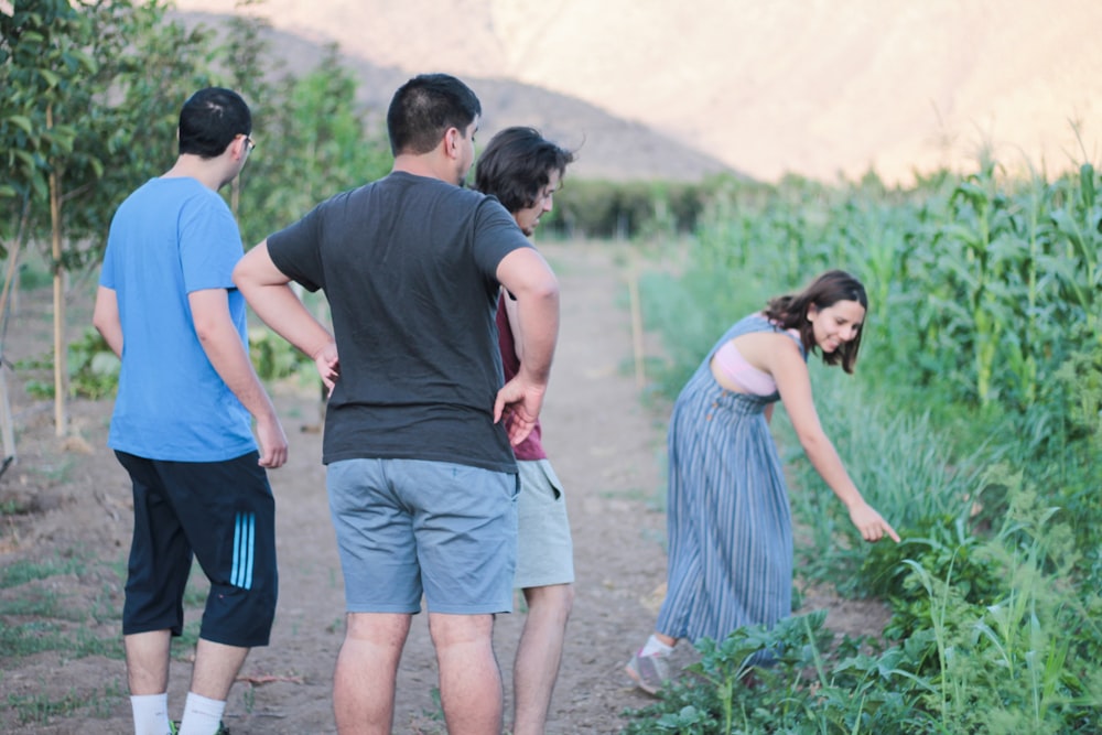 man in blue t-shirt and woman in blue dress walking on dirt road during daytime