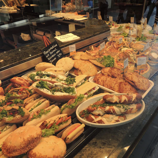 Brightly lit display of fresh sandwiches neatly arranged on wooden shelves inside a UK convenience store.