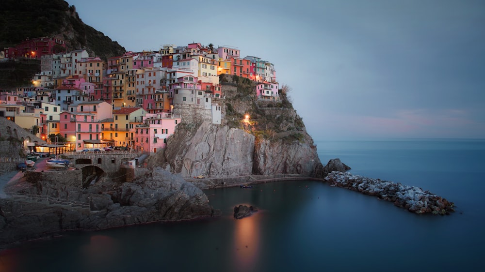 city buildings on rocky mountain beside body of water during night time