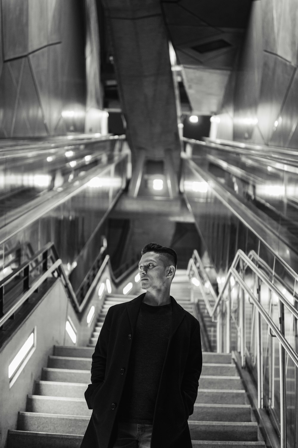 man in black suit standing on escalator