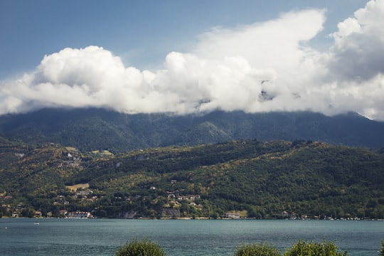 green mountain near body of water under white clouds and blue sky during daytime in Annecy France