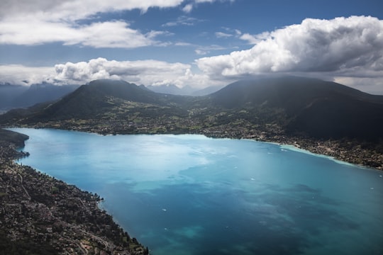 blue lake surrounded by mountains under blue sky during daytime in Annecy France