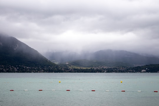 people riding boat on sea near mountain during daytime in Annecy France