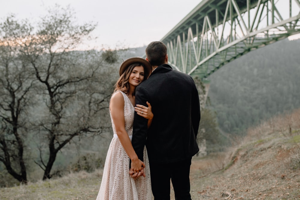 man in black suit standing beside woman in white dress