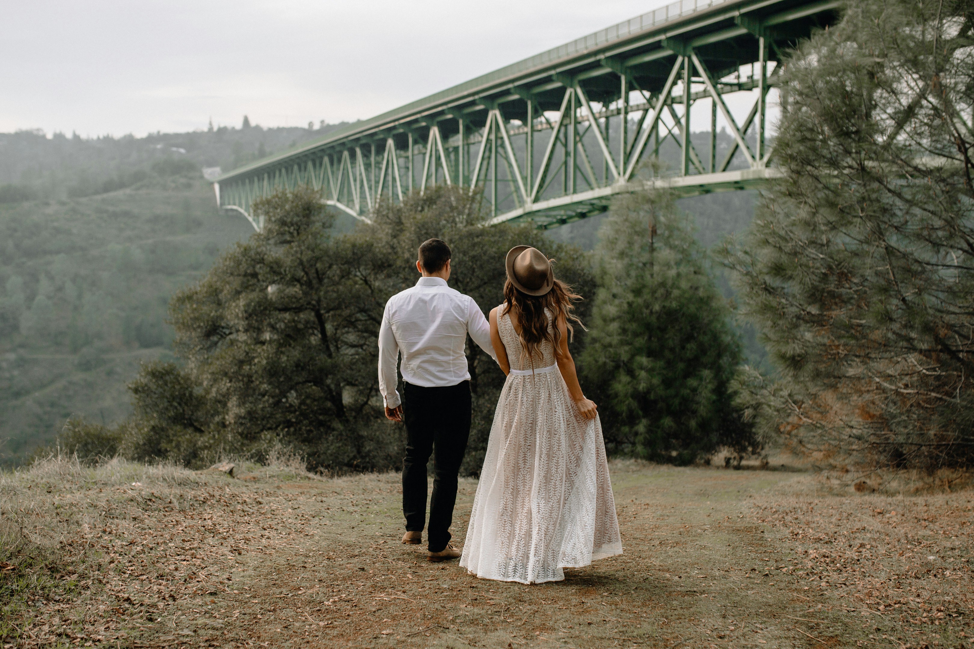 A couple standing near a bridge in a scenic Sacramento area, looking at homes