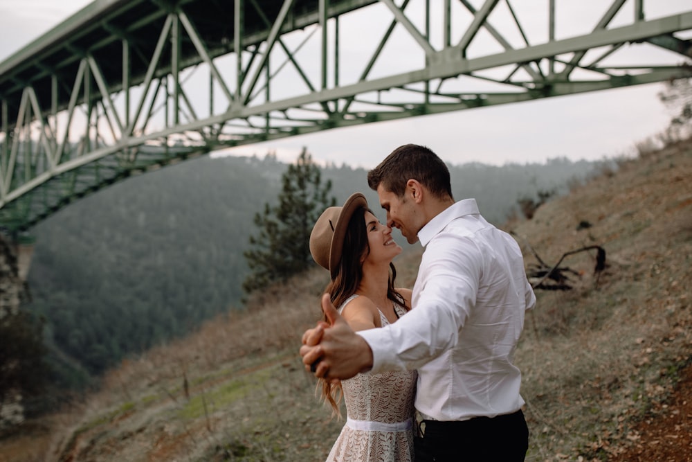 man in white dress shirt kissing woman in brown and white dress during daytime