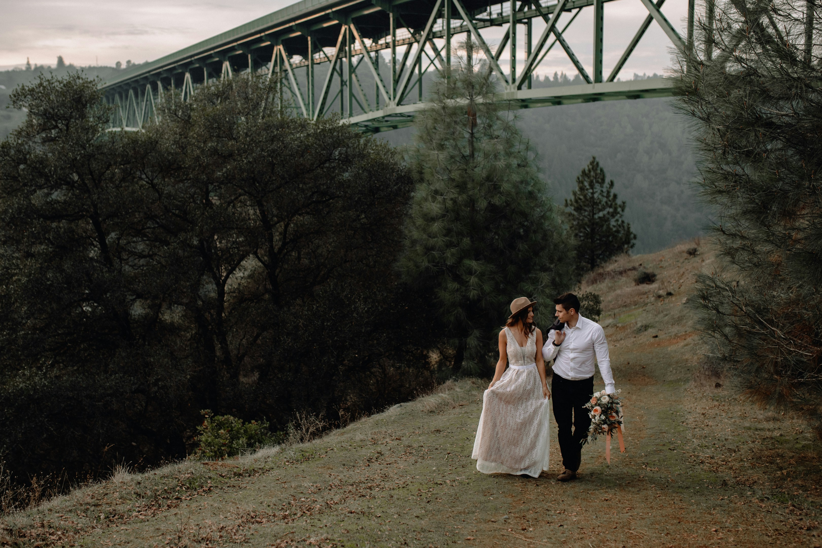 man and woman standing on brown grass field near green trees during daytime
