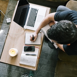 person in black t-shirt sitting at the table using macbook pro