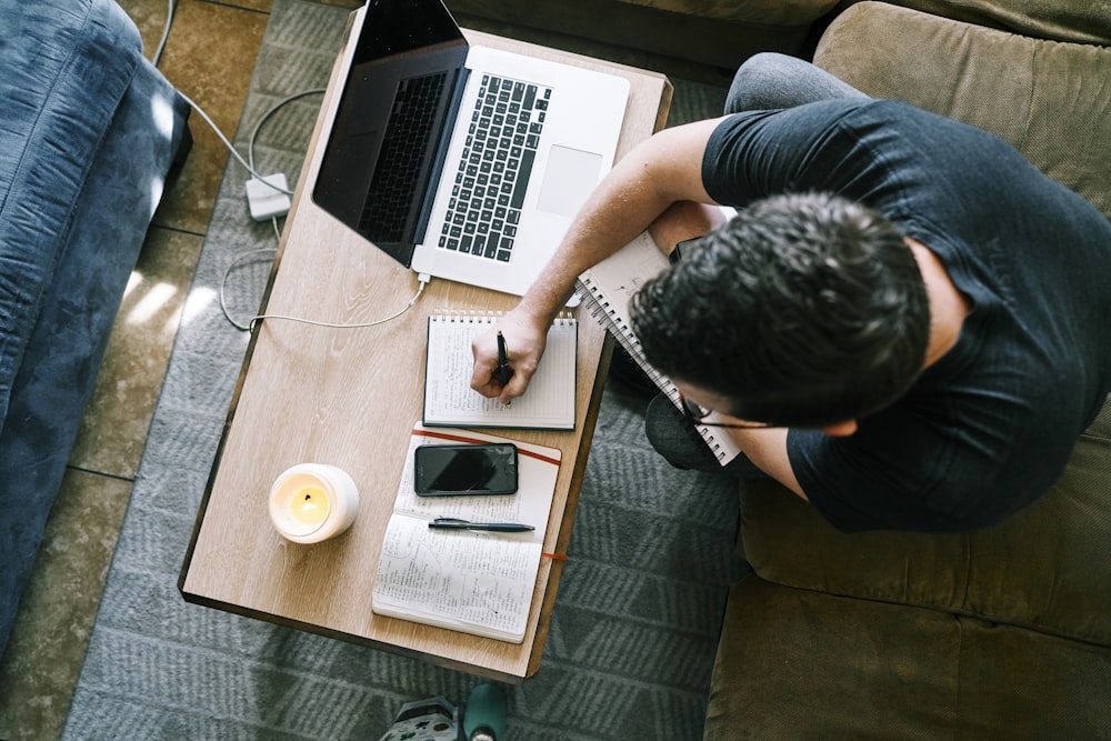 Homme en t-shirt noir assis à la table à l’aide d’un MacBook Pro