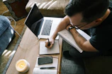 A cozy setting with a person journaling prayers beside a lit candle and the app on tablet