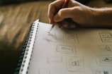 A close-up of hands sketching ideas in a notebook.