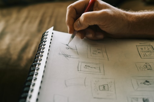 A close-up of a designer's hands sketching ideas on a notepad.