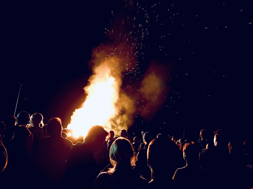 pessoas em pé na frente do fogo durante a noite