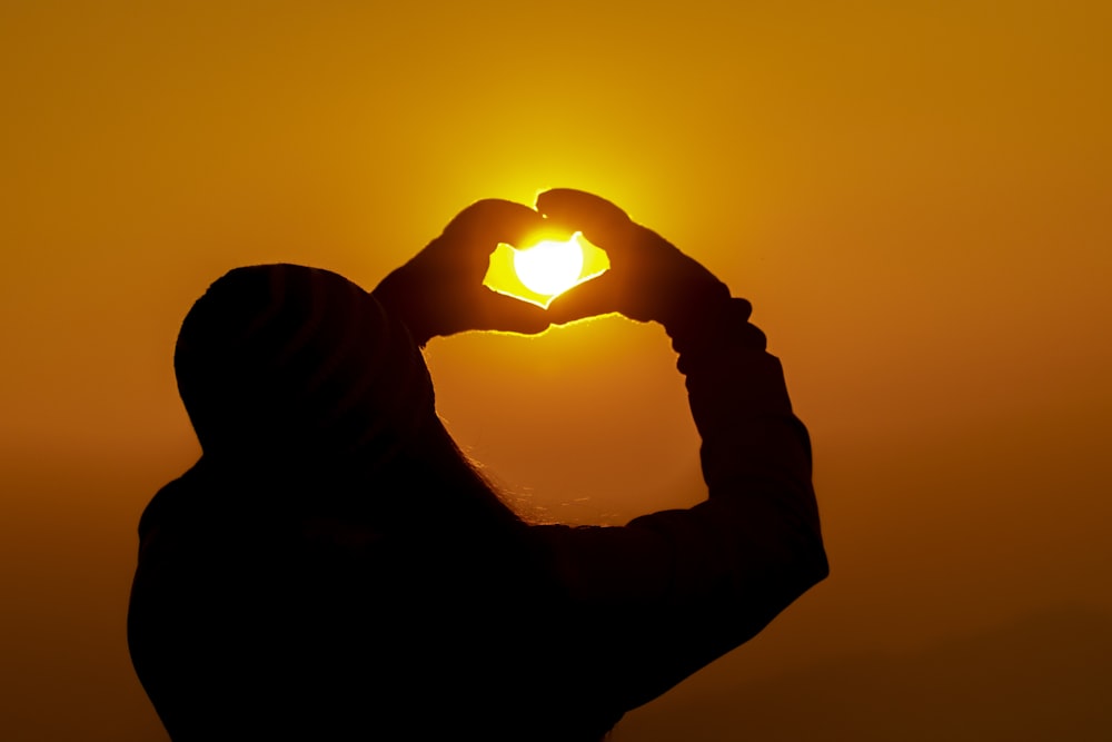 silhouette of man holding sun