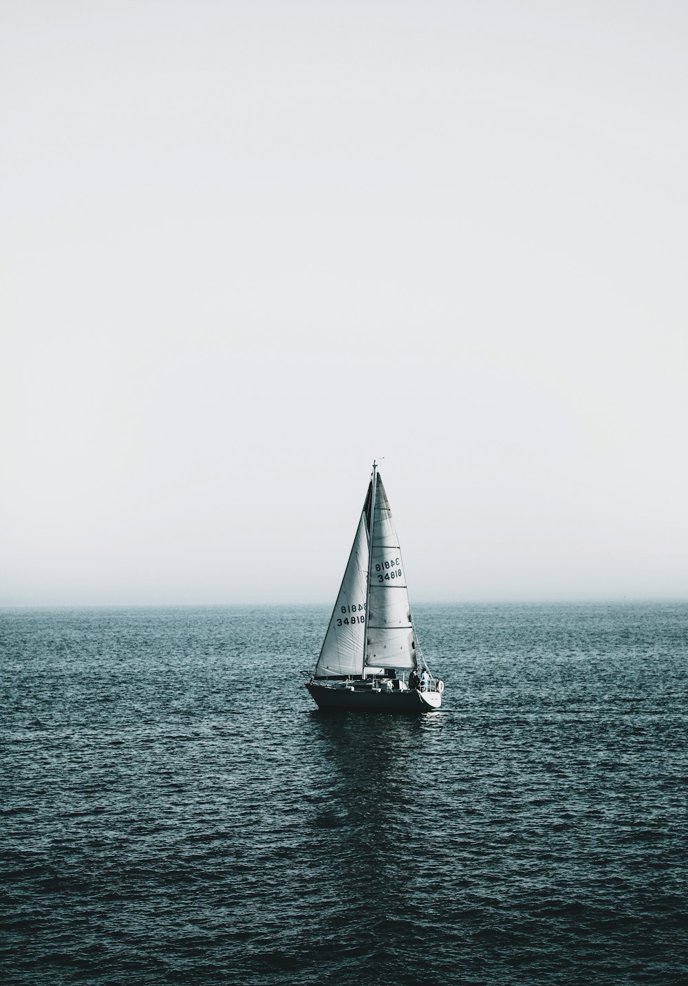 white sailboat on sea under white sky during daytime