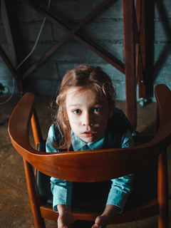 A young Ukrainian girl sitting quietly by a window, sunlight casting soft shadows on her thoughtful face.