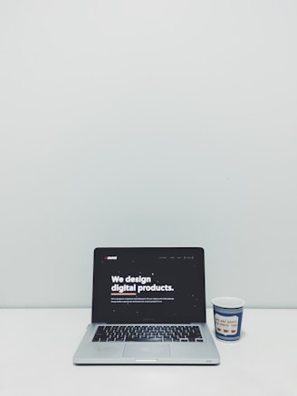 macbook pro beside white and blue plastic cup