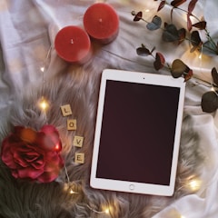 A smiling person watching a tutorial video on a tablet while setting up romantic decor.
