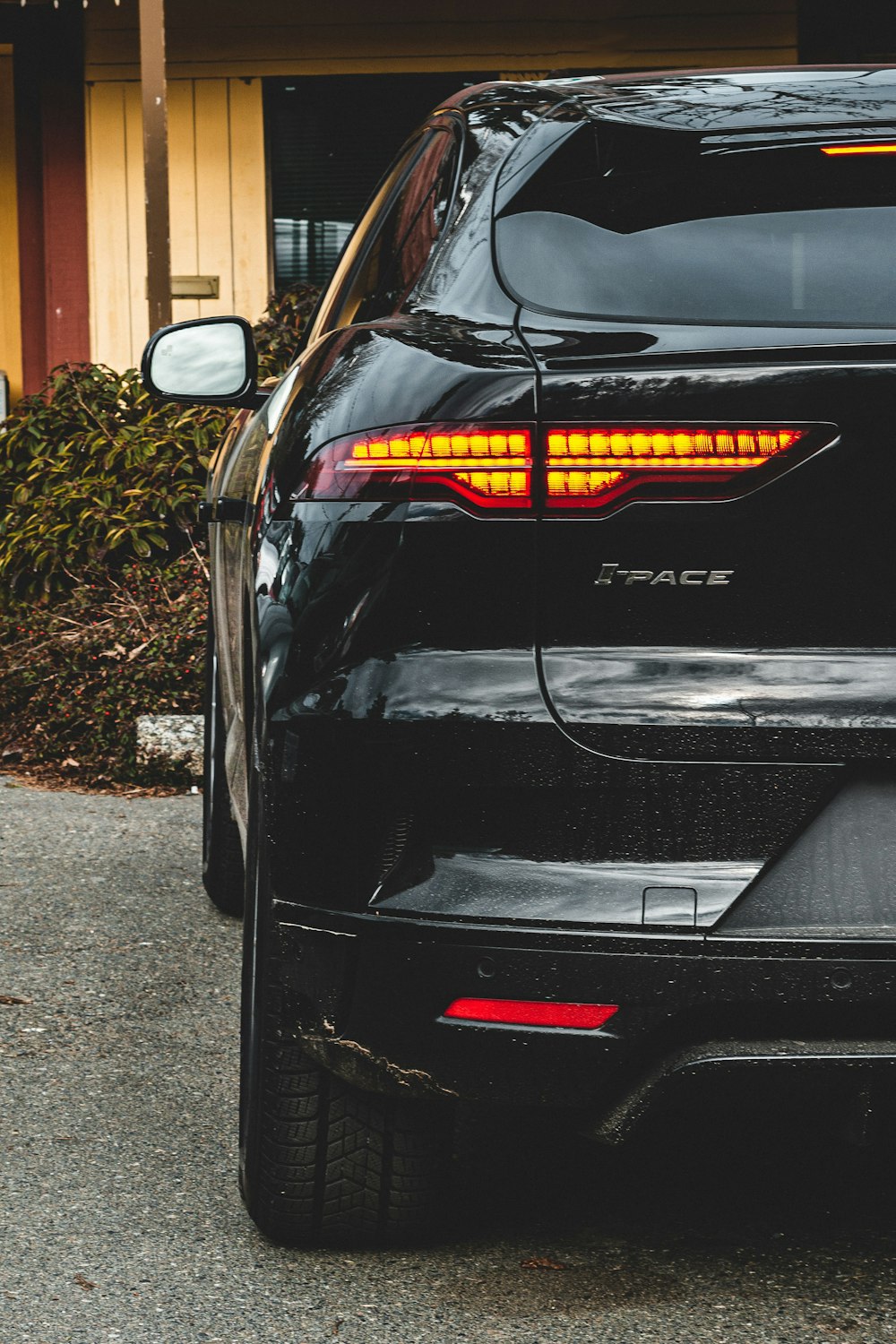 black car parked near brown wooden house during daytime