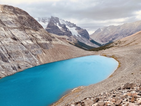 blue lake surrounded by rocky mountains during daytime