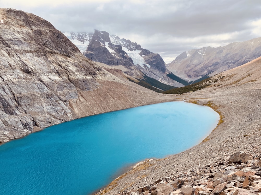 blue lake surrounded by rocky mountains during daytime