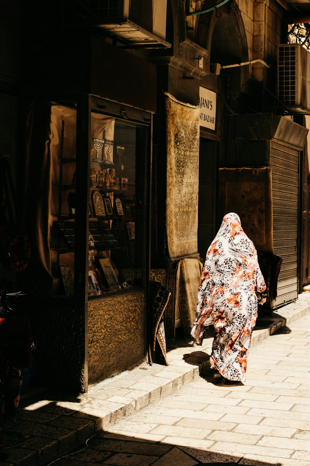 woman in white and red floral hijab standing near store