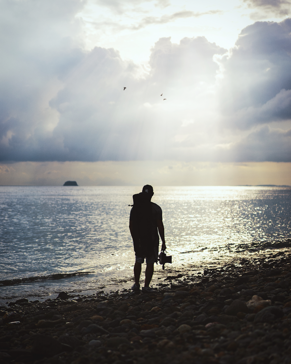 silhouette of man standing on seashore during daytime