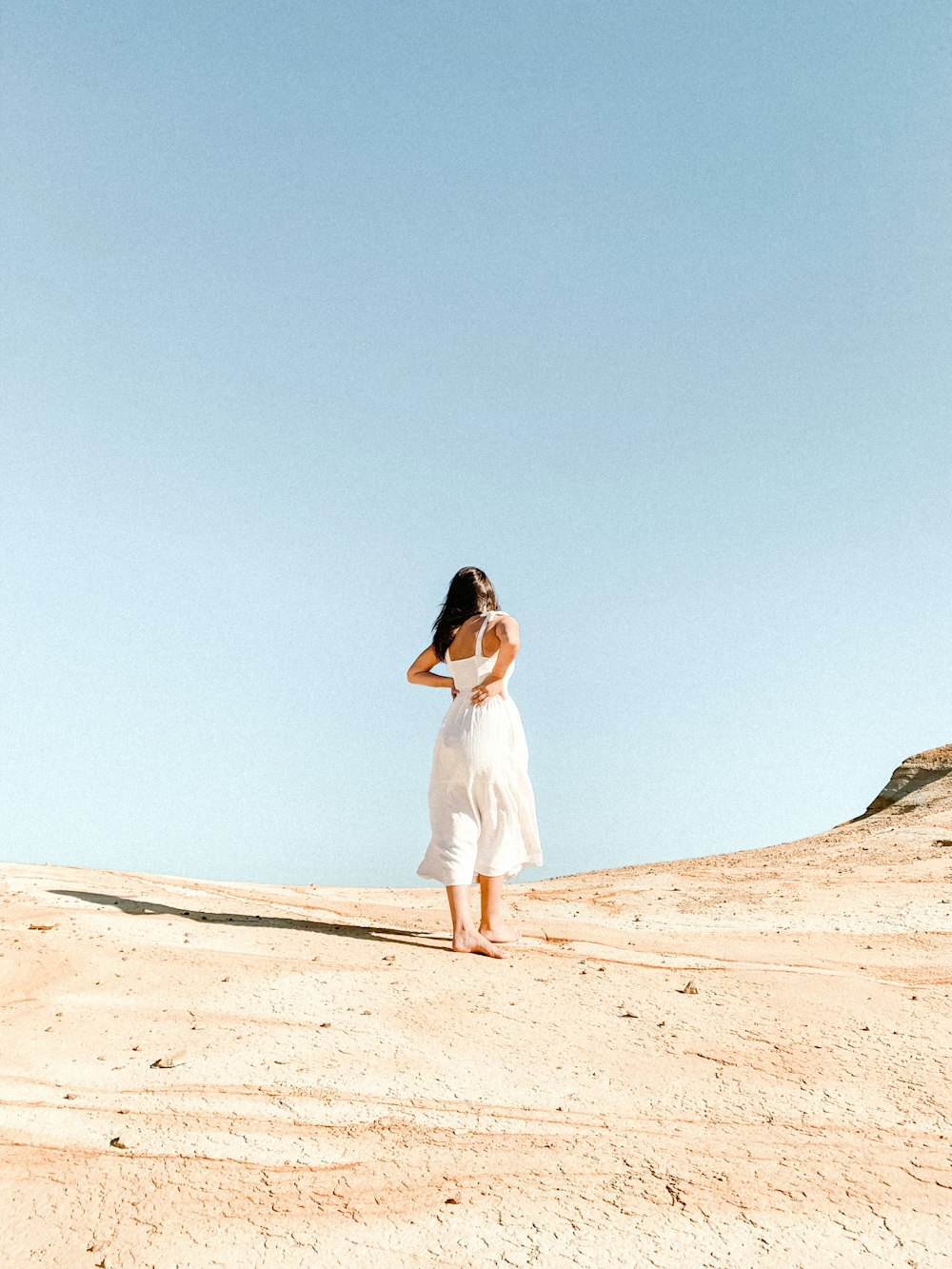 woman in white dress standing on brown sand during daytime