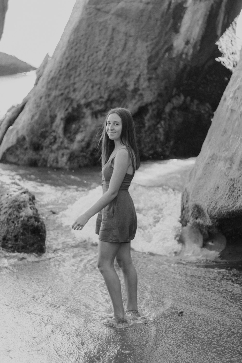 woman in white tank top and black shorts standing on beach shore