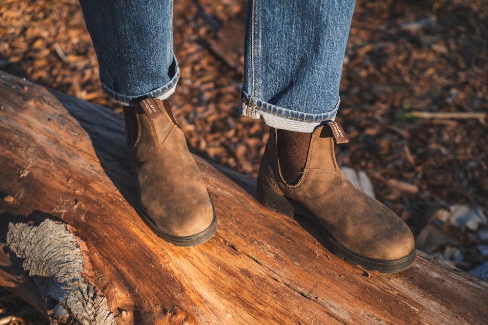 person in blue denim jeans and brown leather boots