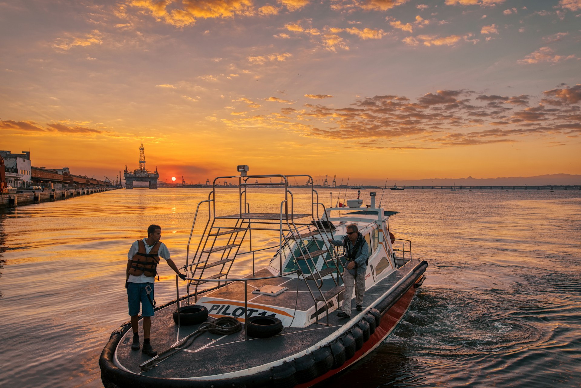man in blue shirt standing on boat during sunset