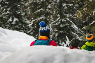 person in blue jacket and red pants sitting on snow covered ground during daytime