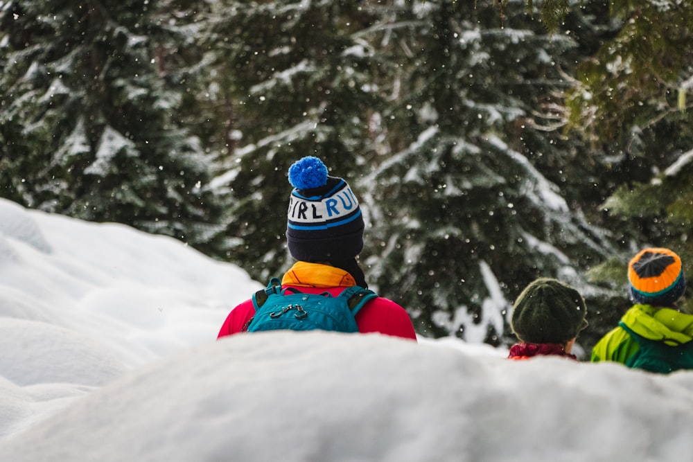 person in blue jacket and red pants sitting on snow covered ground during daytime