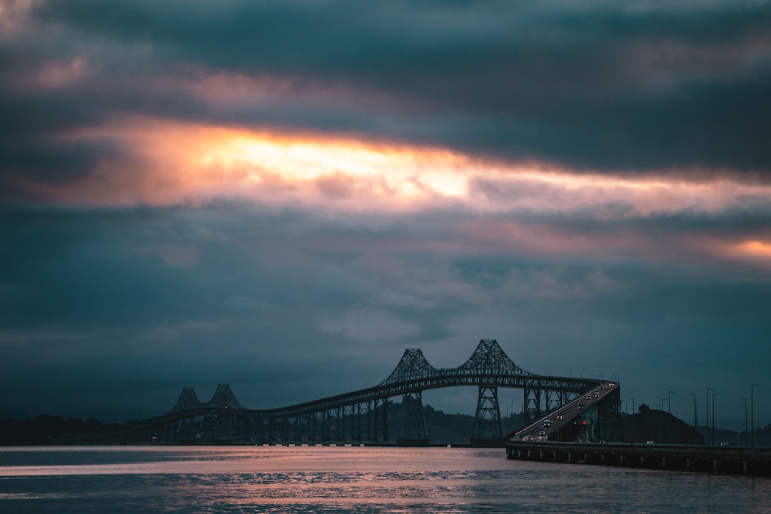 silhouette of bridge under cloudy sky during sunset