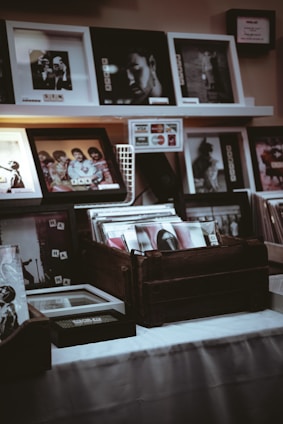 A moody, dark-themed artist studio with vinyl records and merchandise displayed.