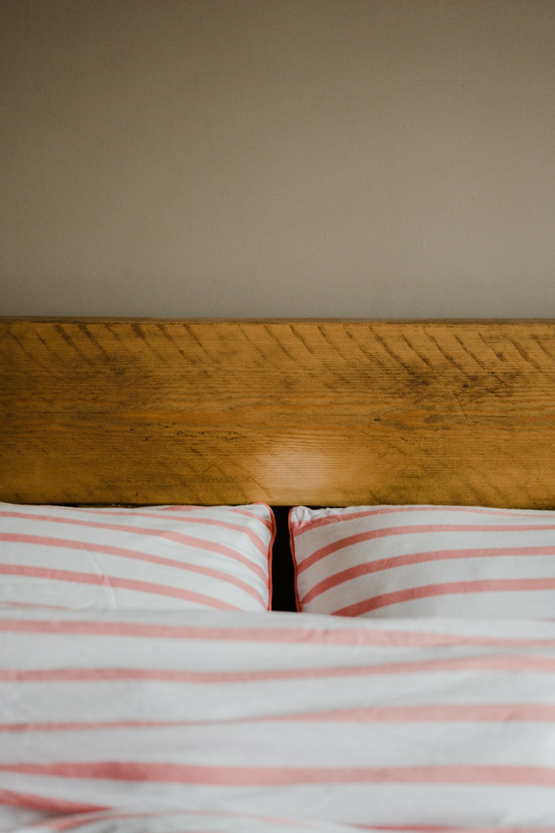 brown wooden bed frame beside white red and blue stripe textile