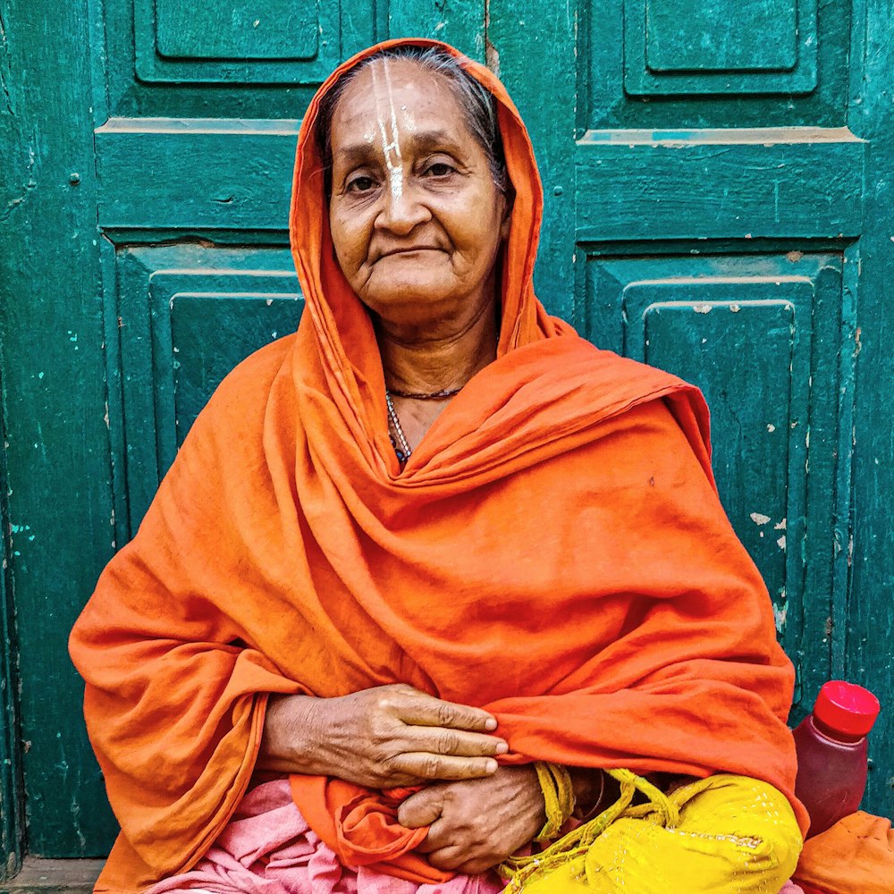 man in red hijab sitting beside green wooden wall