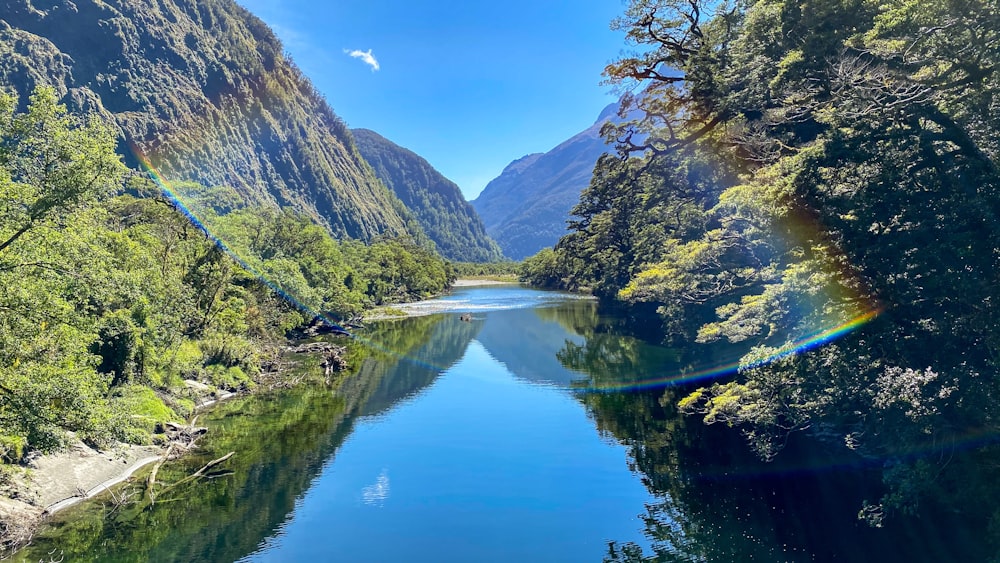 green and brown mountains beside river under blue sky during daytime