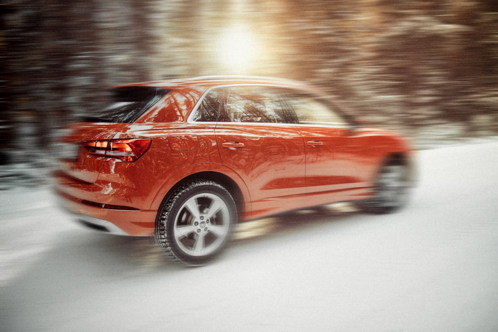 red sedan on snow covered road during daytime