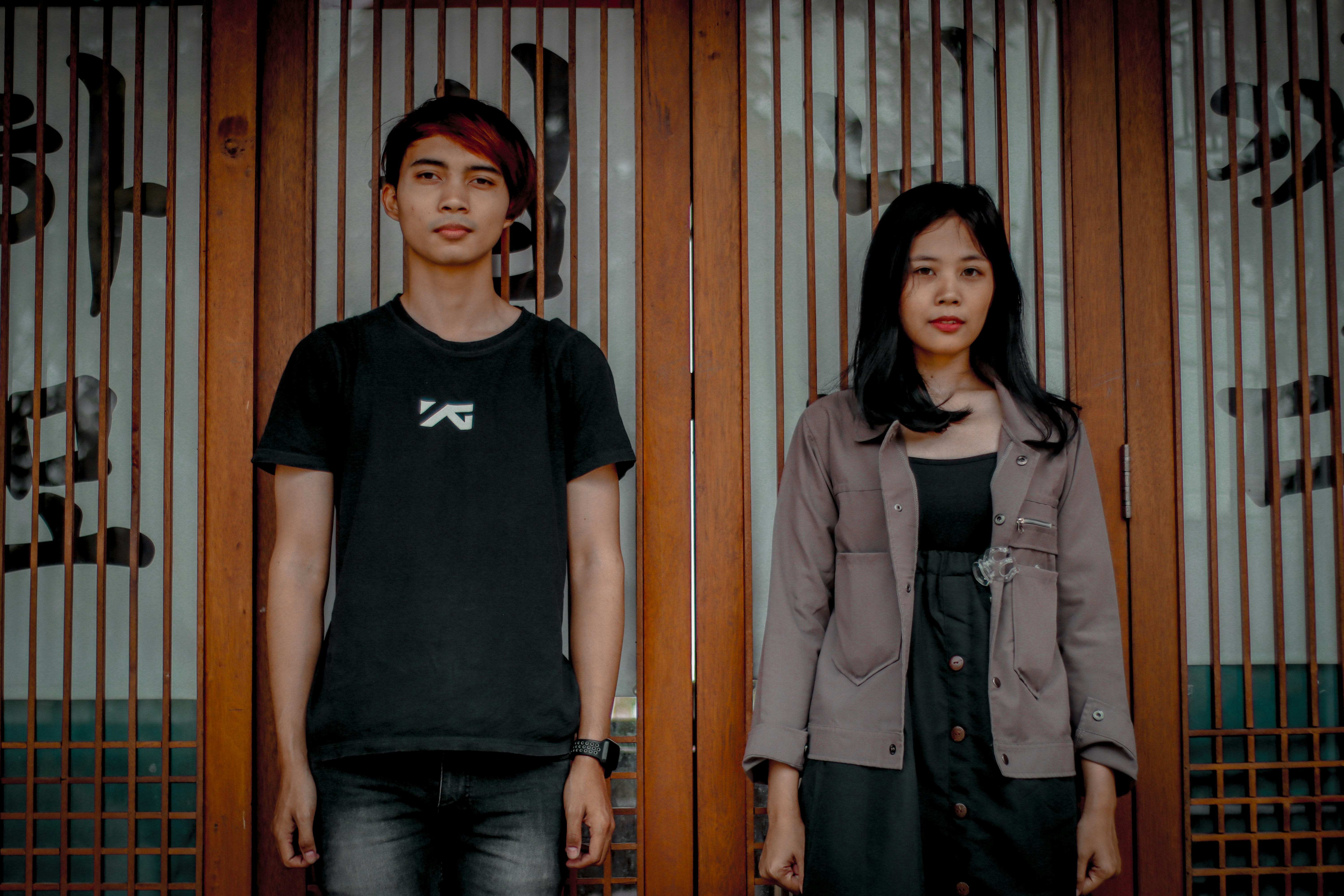Wanita dengan kaos leher kru hitam berdiri di samping wanita dengan jaket abu-abu