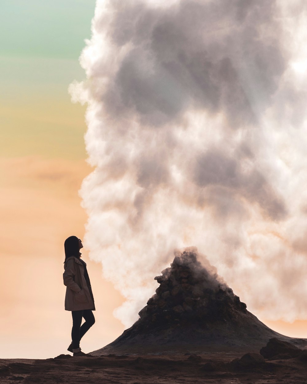 man in black jacket standing on rock formation under white clouds during daytime